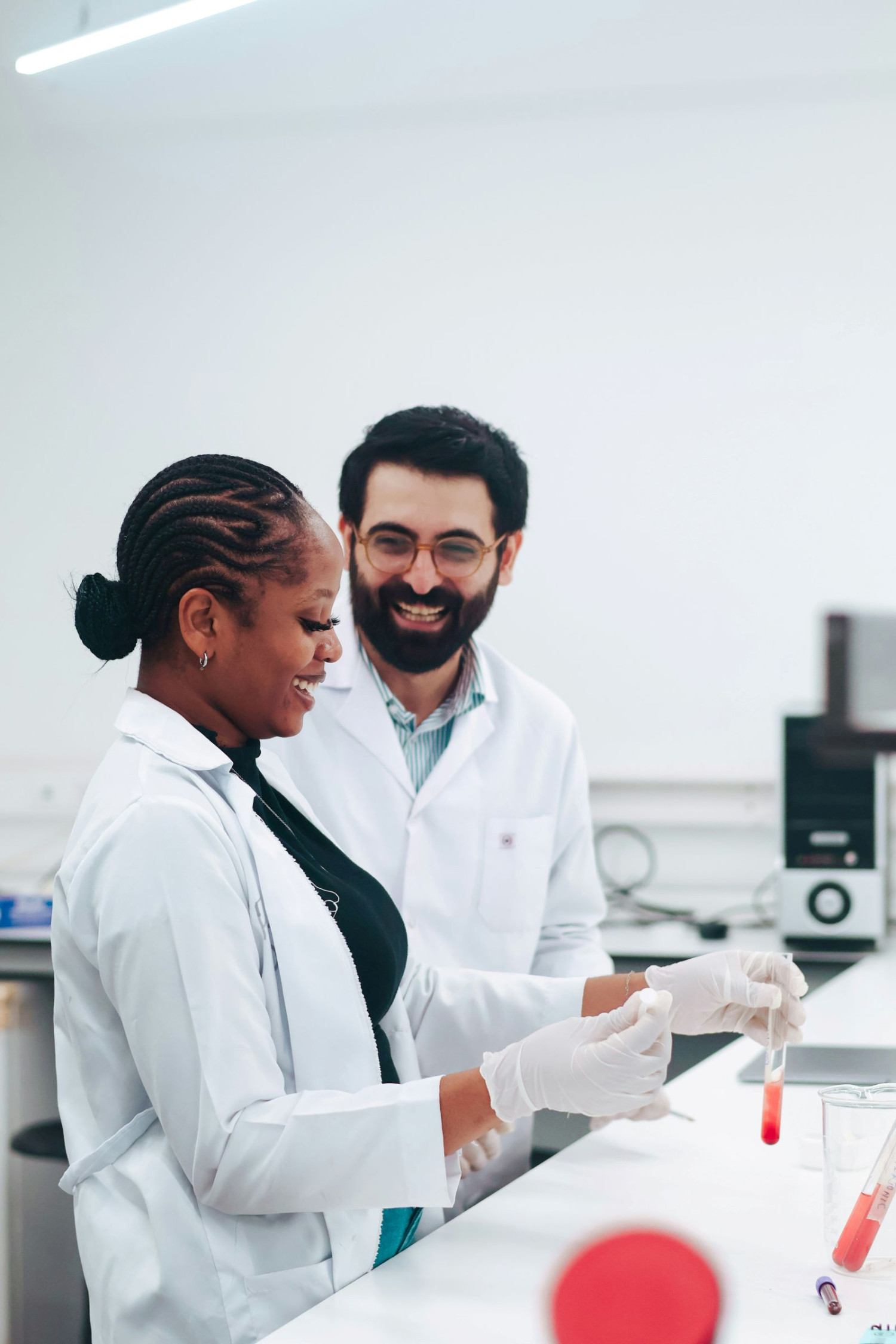 Zwei Wissenschaftler im Labor analysieren Proben und lächeln.
