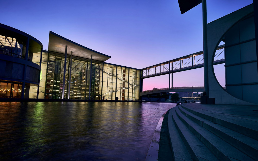 Moderne Glasgebäude am Wasser bei Sonnenuntergang in Berlin.