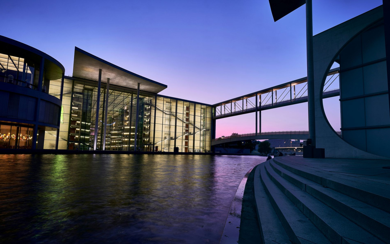 Moderne Glasgebäude am Wasser bei Sonnenuntergang in Berlin.
