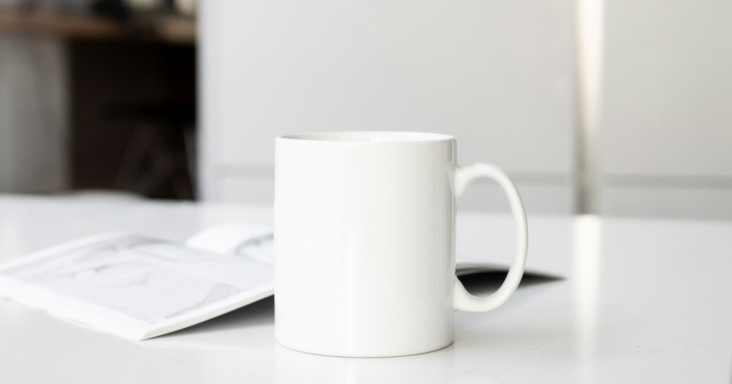 Eine weiße Tasse und ein aufgeschlagenes Magazin auf einem Tisch