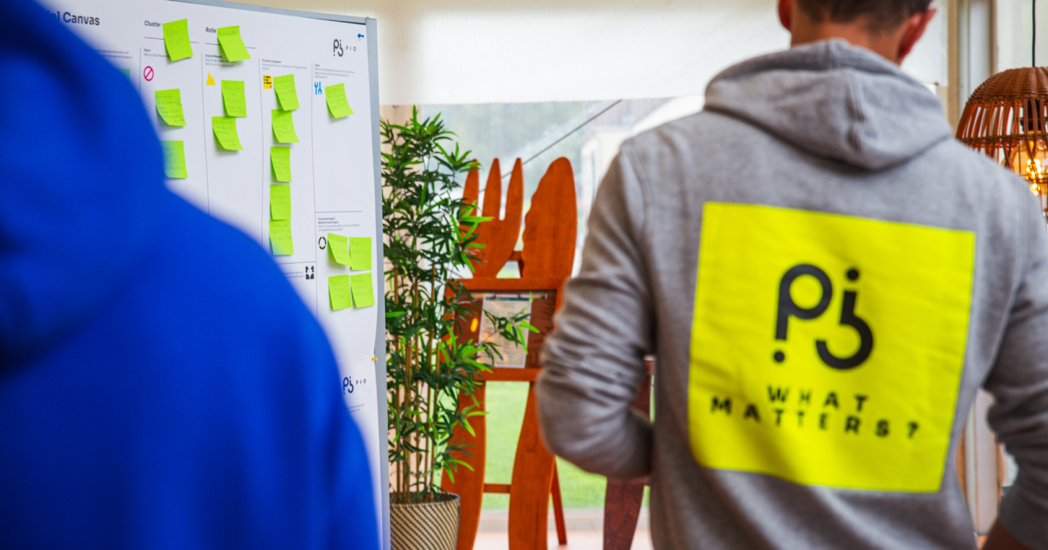 Eine Person mit einem Kapuzenpulli mit der Aufschrift "What Matters?" steht vor einem Kapa Board.
