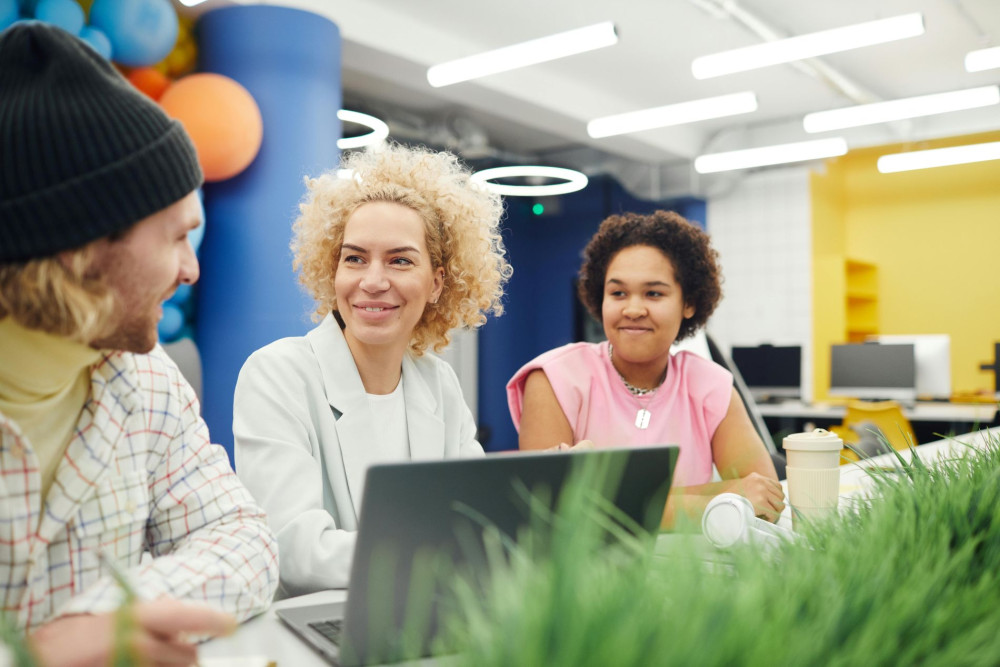Drei Personen unterhalten sich freundlich in modernem Büro.