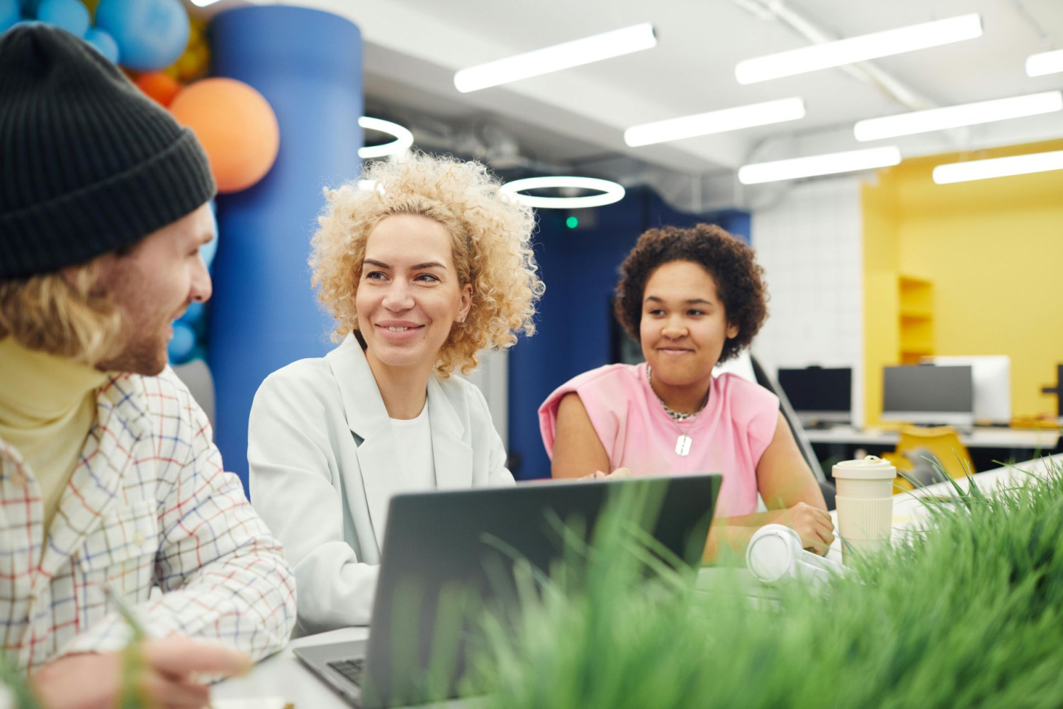 Drei Personen unterhalten sich freundlich in modernem Büro.