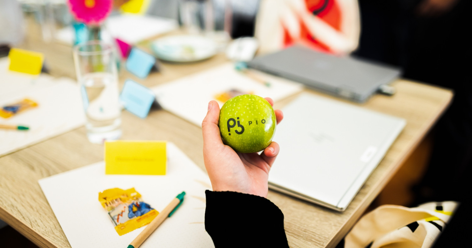 Rebranding bei PIO - eine Mitarbeiterin hält einen gebrandeten Apfel in der Hand.