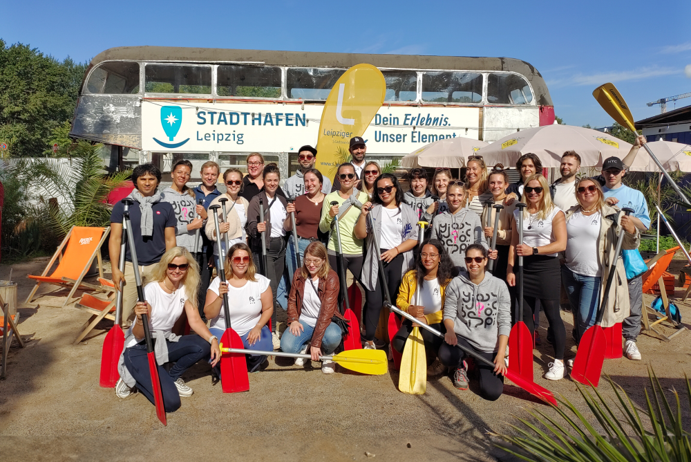 The PIO team stands together with paddles in their hands at Leipzig city harbor.