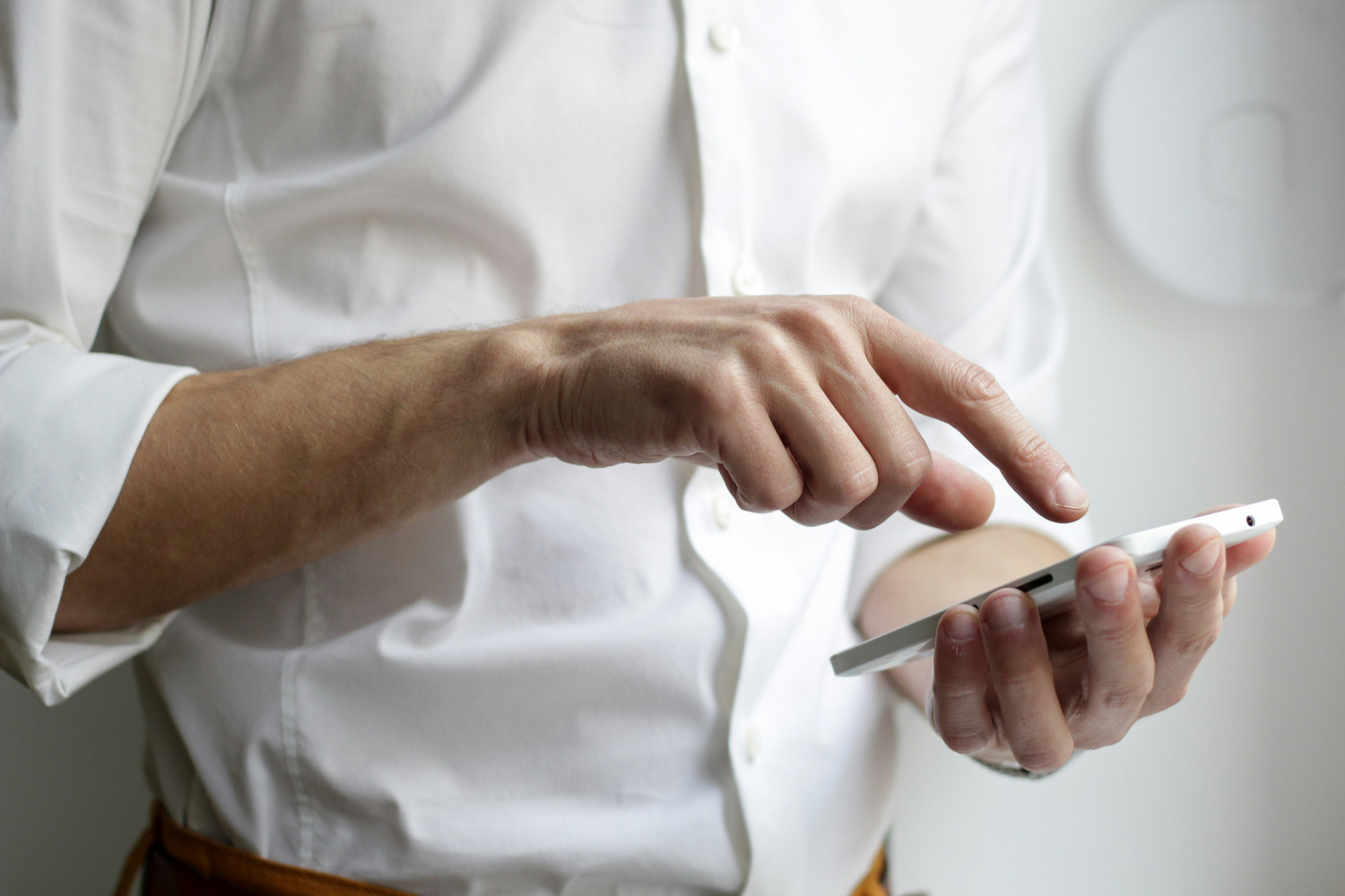 Eine Person hält ein Smartphone in der Hand und tippt mit dem Finger darauf.