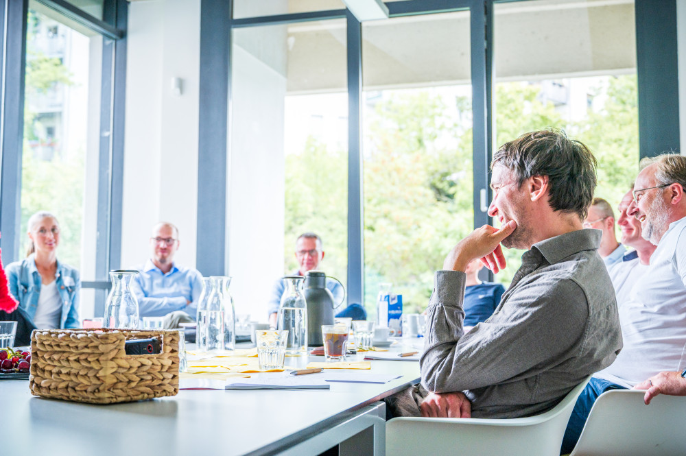 Mehrere Personen sitzen in einem Workshop an einem großen Tisch.