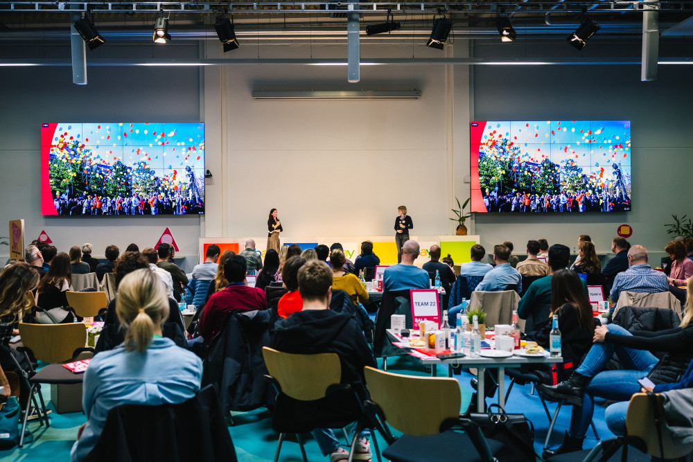 Ein Saal voller Menschen hört einem Vortrag von zwei Personen auf einer Bühne zu