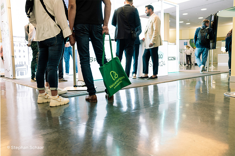 Menschen auf einer Messe mit Kleinanzeigen Immobilien-Beutel