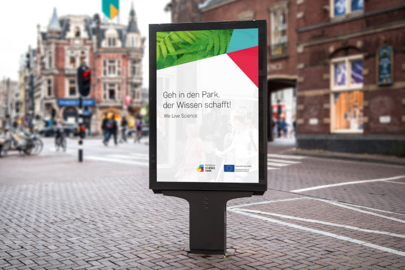 Ein Citylight-Poster des Potsdam Science Park in einer Fußgängerzone mit dem Schriftzug "Geh in den Park, der Wissen schafft."