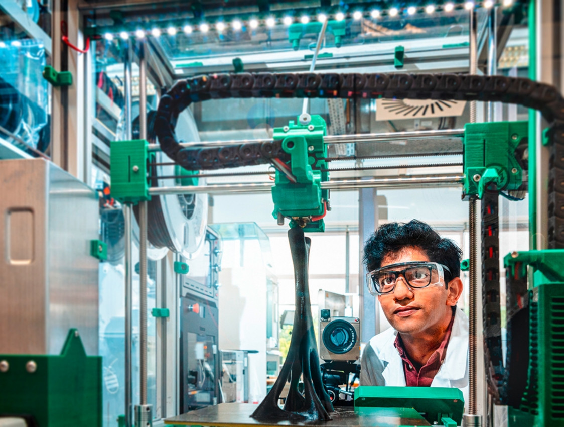 Scientist observing a machine in the Potsdam Science Park. He is wearing safety goggles and a protective suit.