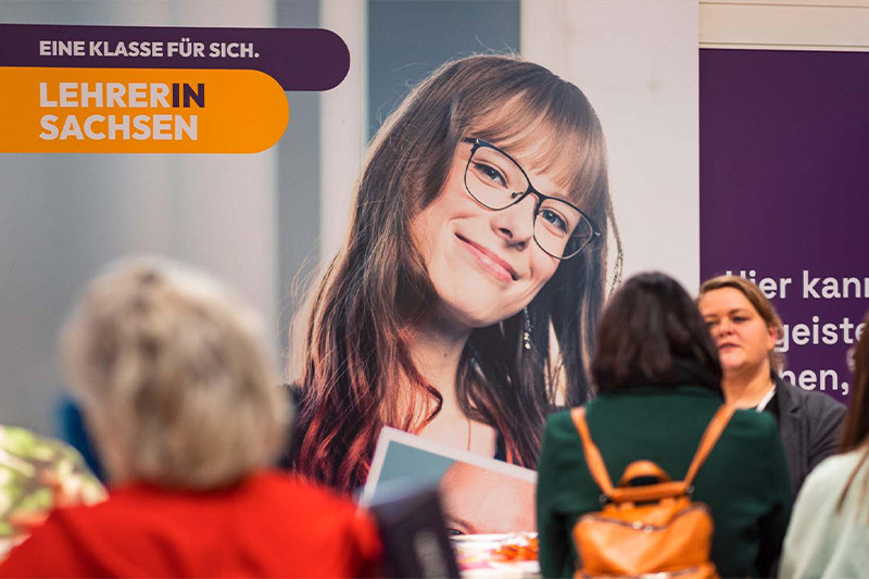 LEHRERIN SACHSEN's exhibition stand, where several people are chatting
