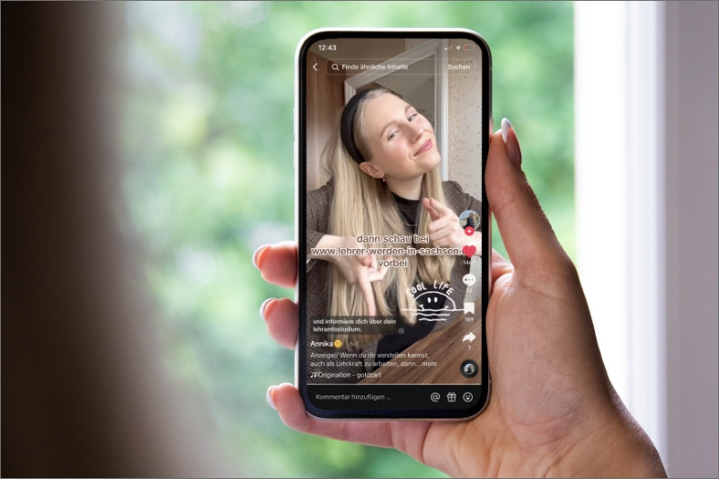 Eine Person hält ein Smartphone in der Hand, auf dem ein TiKTok von "Eine Klasse für sich. Lehrer in Sachsen." läuft.