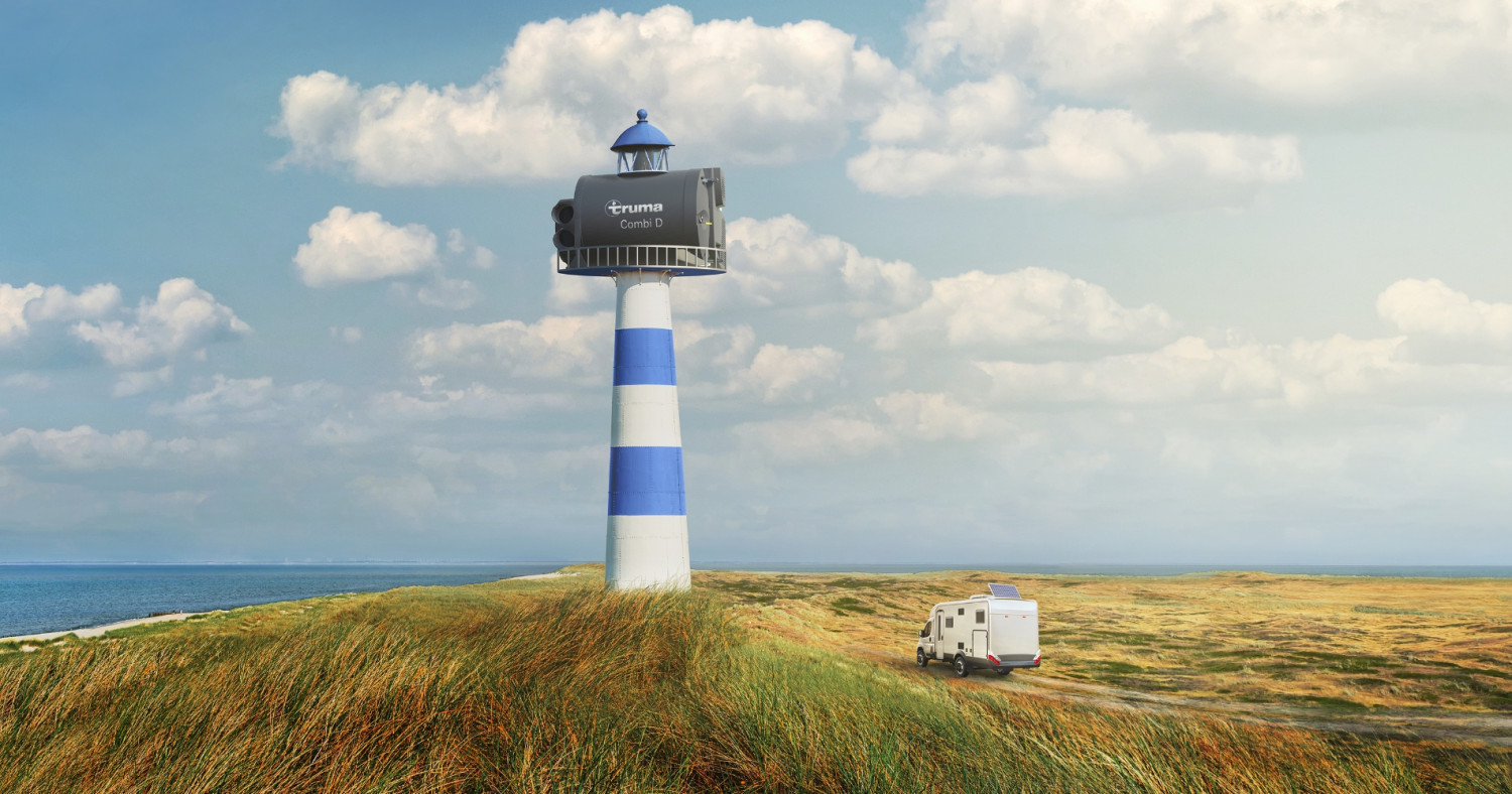 Leuchtturm mit Truma-Aufschrift und Wohnmobil in den Dünen an der Küste