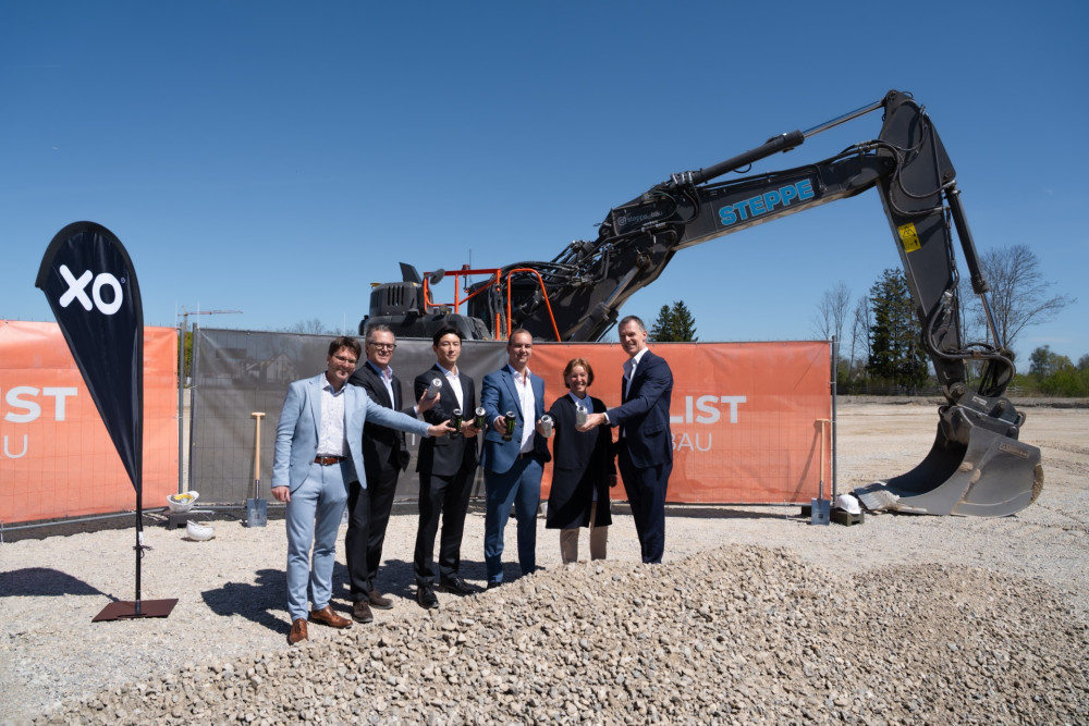 Mehrere Personen stehen auf einer Baustelle beim Spatenstich von XOLUTION