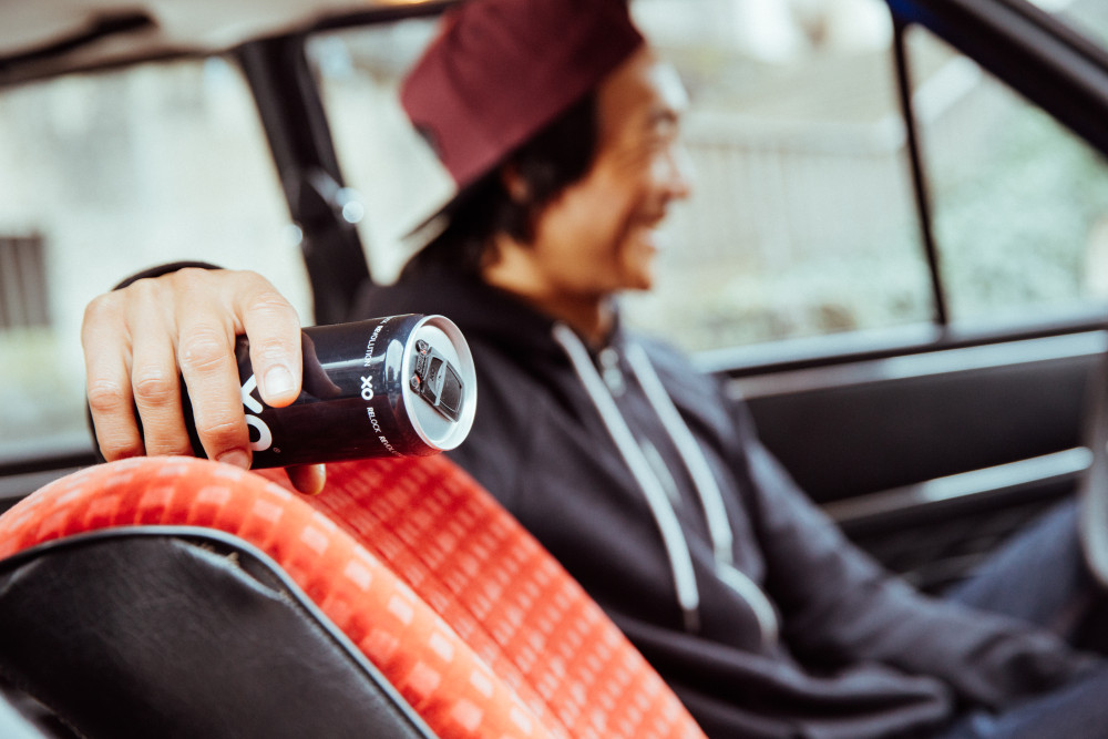 Ein Mann sitzt in einem Auto und hält in der Hand eine Getränkedose mit XOLUTION-Verschluss